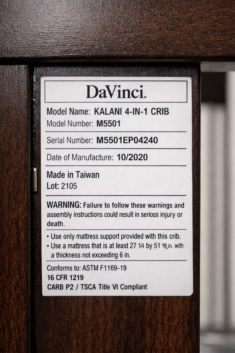 DaVinci crib manufacturer label showing model name and identifying information attached to the crib frame