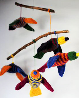 Homemade DIY knit tropical birds for a baby crib mobile in a forest birds theme nursery