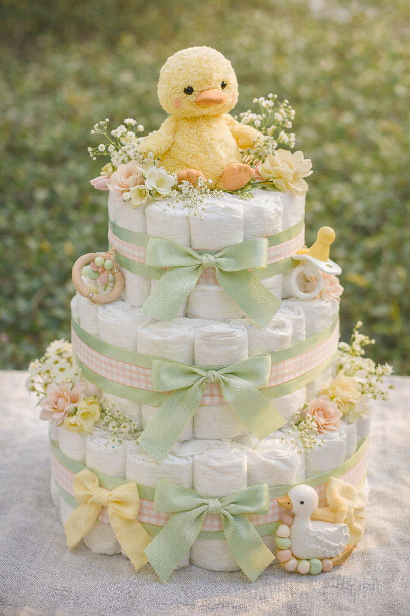 Pastel spring duck themed diaper cake with soft yellow duckling topper at a baby shower