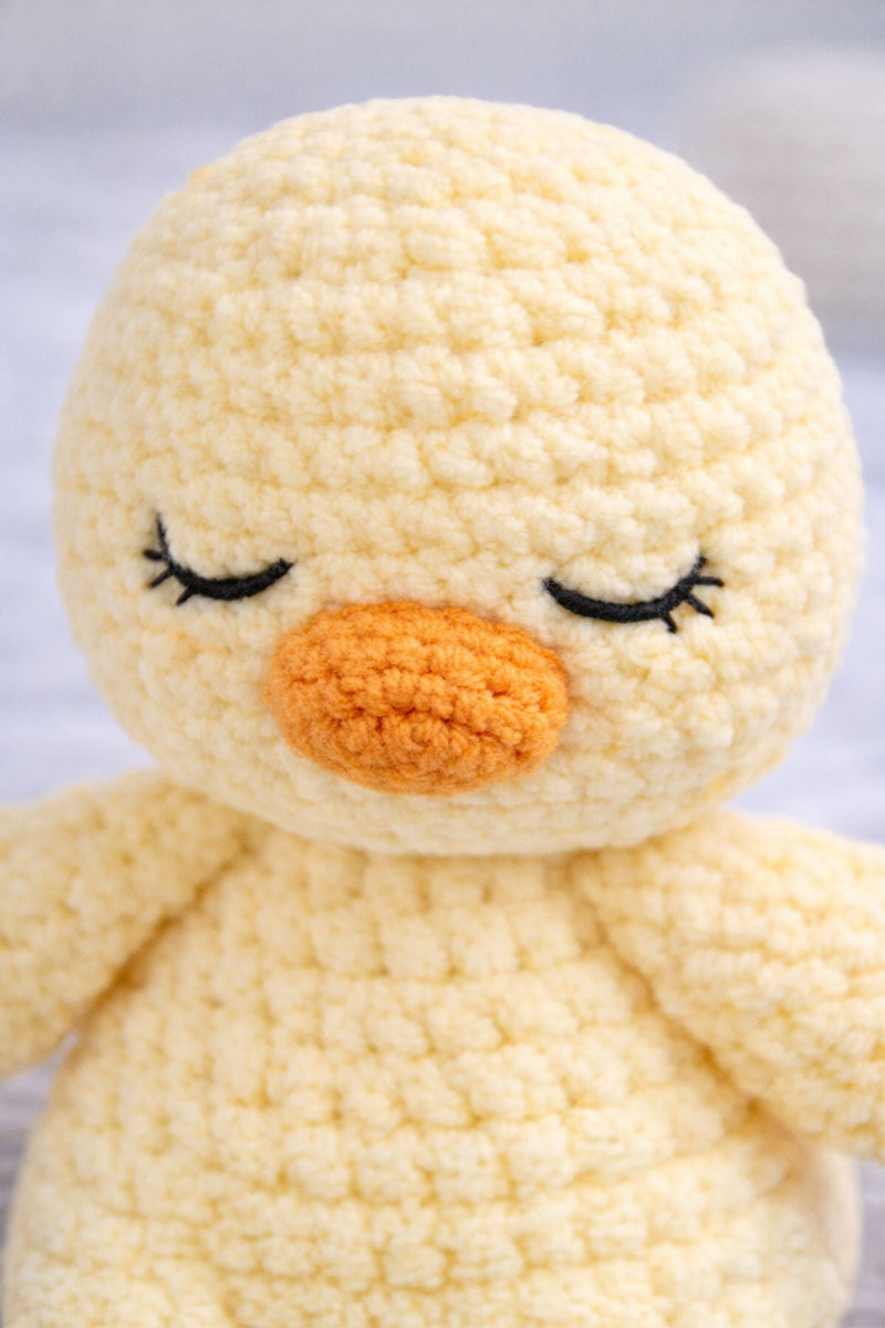 Close view of embroidered eyes and shaped face on crochet duck lovey
