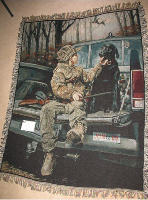 Ducks Unlimited throw blanket featuring a young boy sitting in the back of a truck with his black Labrador hunting dog