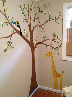 Baby Maddie loves her forest nursery tree wall mural with a colorful toucan and giraffe