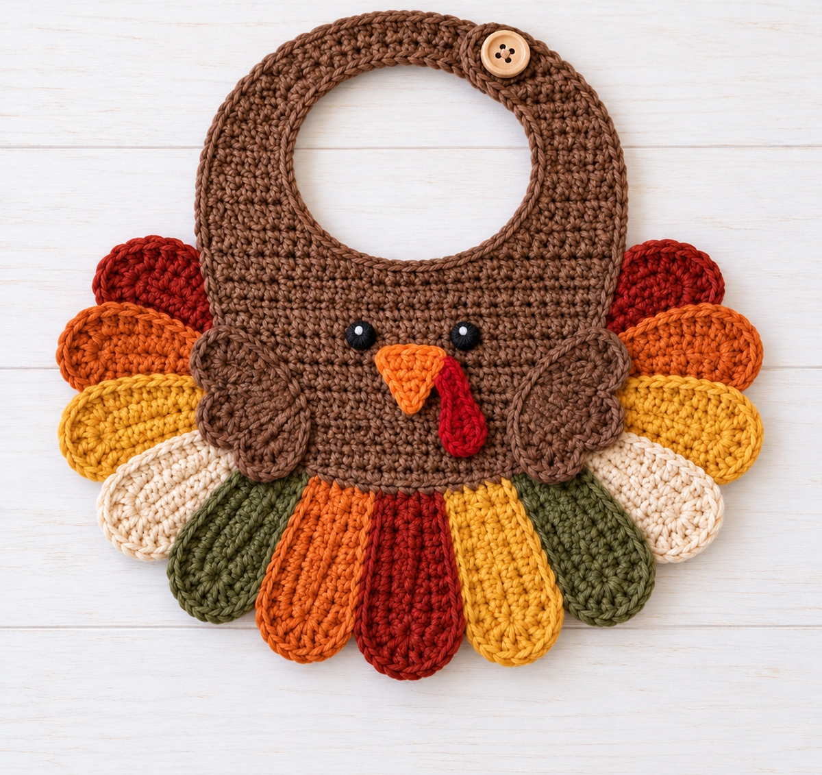 Finished colorful crochet turkey baby bib with turkey face and fan-shaped tail feathers for the free turkey bib crochet pattern