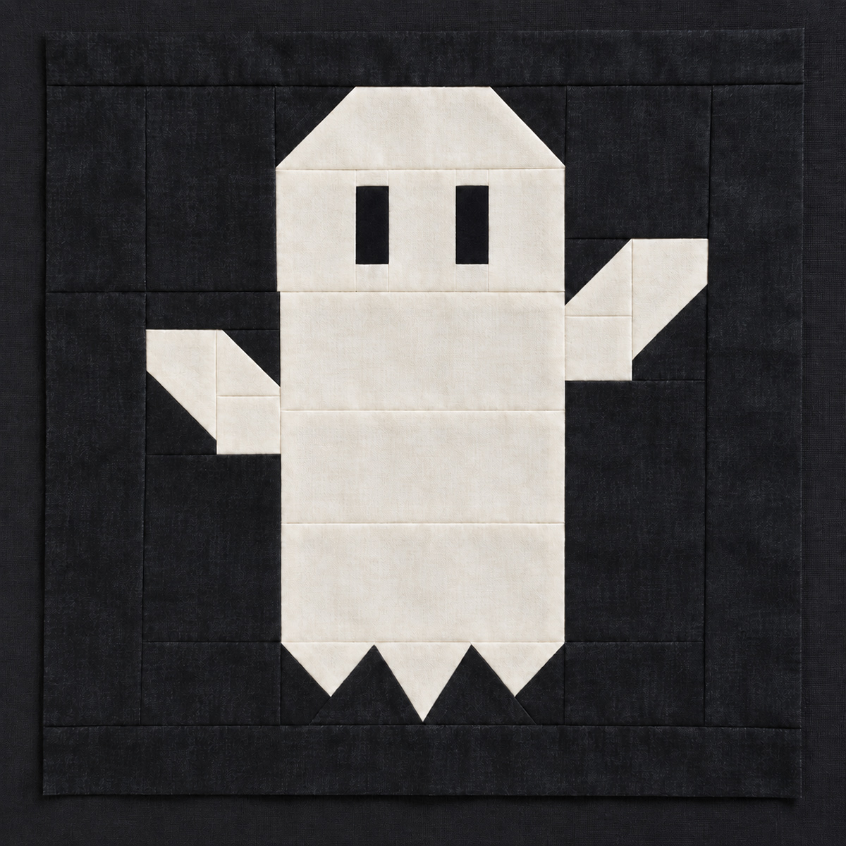 Pieced white ghost quilt block on a dark Halloween background