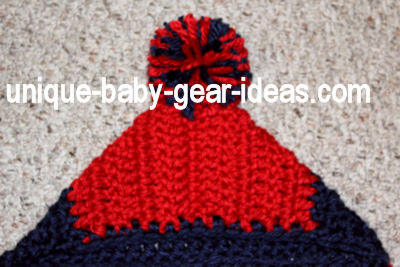 Large pom pom made from thick super chunky red and blue yarn for a crochet hooded baby bunting crochet for a baby Ole Miss fan