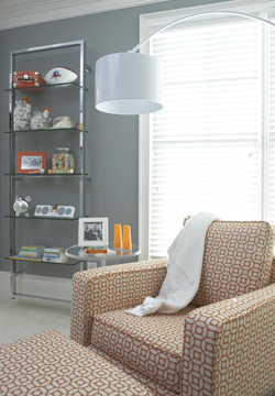 Modern orange and white upholstered nursery chair with a chrome floor lamp
