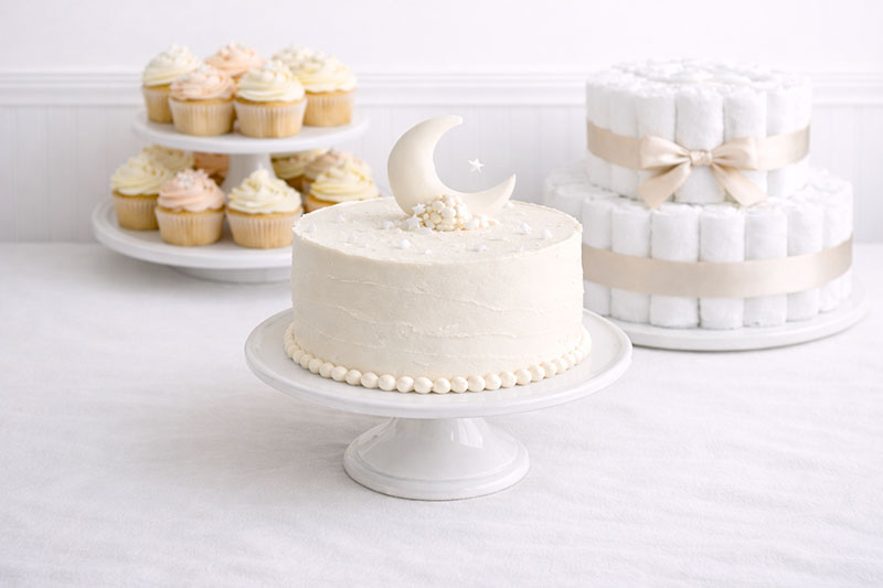 Baby shower cake centered on a coordinated dessert table with plates and serving setup