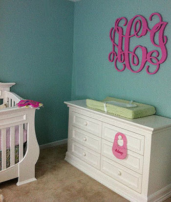Elegant pink teal and white baby girl nursery room with large painted wooden wall letters featuring a baby girl's initials in a circular monogram