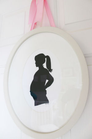 Framed maternity silhouette hung by a pink satin ribbon