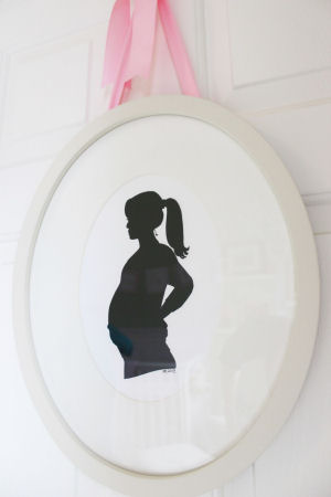Framed maternity silhouette hung by a pink satin ribbon