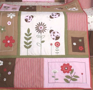 Patchwork baby crib quilt with pink and brown ladybug appliques for the nursery room