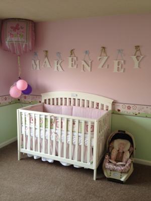 Makenzey's name spelled in letters on her pretty pink nursery wall behind her baby crib