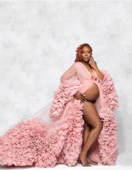 Long pink maternity gown with ruffles, leg split and plunging neckline for a pregnancy portrait photo shoot