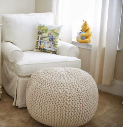 A comfortable nursery chair with a pillow featuring Christopher Robin and Winnie the Pooh