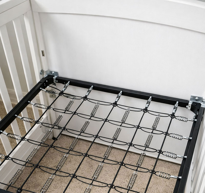 Metal crib mattress support frame with integrated spring grid and corner mounting points inside a crib