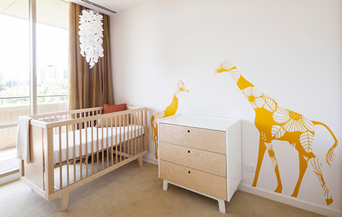 Modern gender neutral giraffe theme baby nursery ideas with large mother and baby giraffe on the wall.