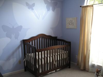 A view of our baby girl's crib, the hand-painted butterflies nursery wall mural in shades of lavender and window treatments. 