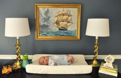 Tall sailing ship print framed in a gold-tone frame in a baby boy's nursery room