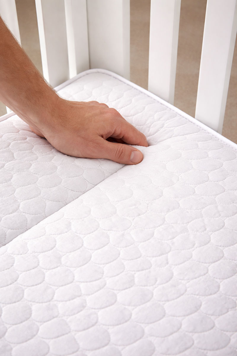 Checking the corner fit of a firm crib mattress in a crib