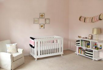 An elegant blush pink baby girl nursery room decorated with metallic gold décor and wall decorations