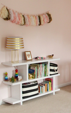 Homemade DIY nursery bookshelf and black and white storage bins in a pink baby girl nursery room