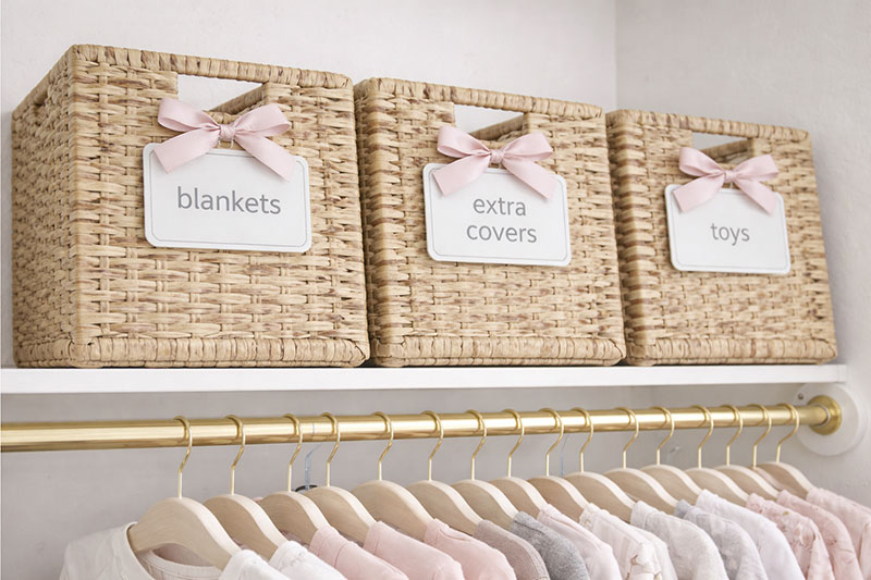Nursery closet baskets and bins used as labeled storage zones for baby supplies