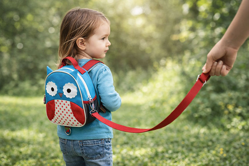 Toddler wearing an owl backpack-style child harness during an outdoor walk