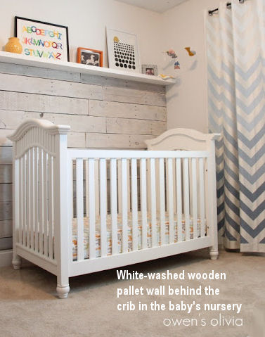 Recycled wooden pallets have been white-washed and used to panel the baby's nursery wall