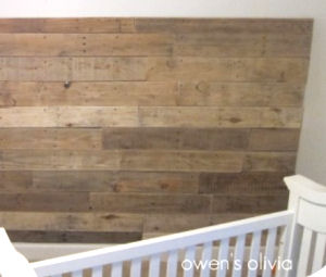 A baby nursery wall paneled with rustic boards from recycled wood pallets