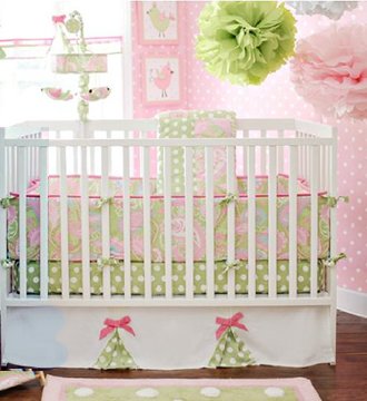 Pink white and lime green baby crib bedding in a baby girl nursery room with tissue paper pompoms