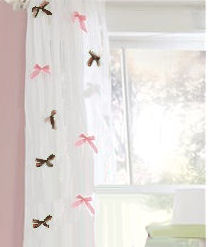 Sheer white curtain panels with pink and chocolate brown bows added to complement a pink and brown baby girl nursery room