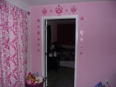 Removable, vinyl Amy Coe wall decals in pink replicate the fabric pattern of the curtain panels and crib set. 