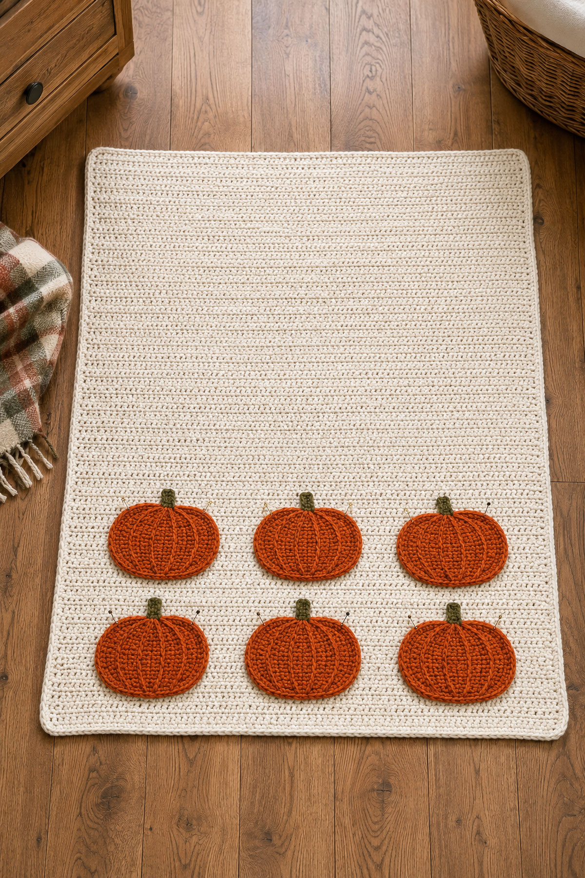 Overhead view showing six crochet pumpkin appliqués positioned in two rows on a cream baby blanket before sewing