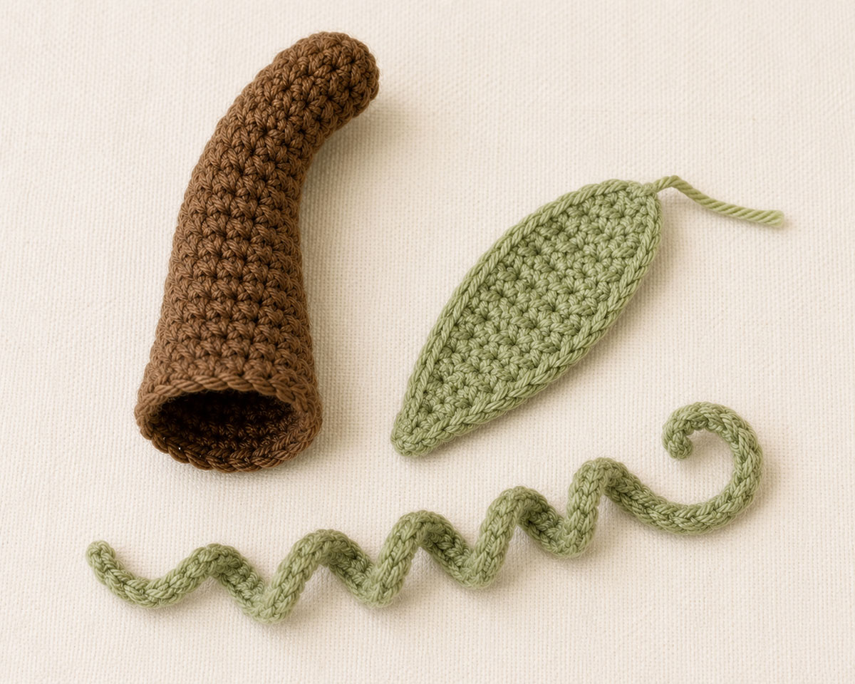 Crocheted brown pumpkin stem with sage-green leaf and curling vine ready to attach to the pumpkin lovey