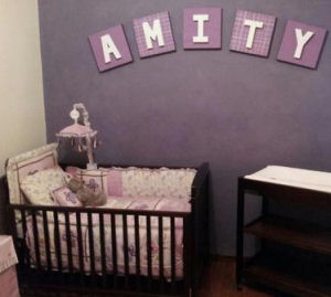 A small baby girl nursery with a purple accent wall