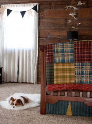 A rustic crib in a baby boy nursery room with a beautiful homemade patchwork crib quilt