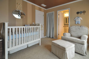 Baby boy nursery with wall stripes painted with taupe color paint and a metallic bronze ceiling