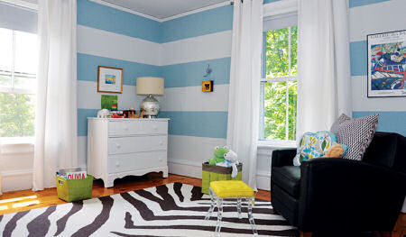 A baby boy nursery room with black and white zebra rug and black leather nursery glider