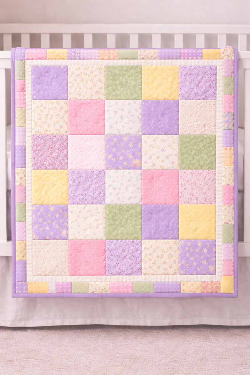simple patchwork crib quilt pattern in spring colors sewn with straight seams