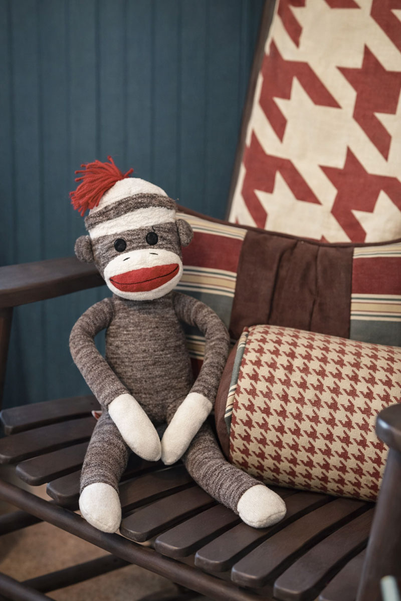A vintage sock monkey in a navy blue and rust baby boy nursery color scheme