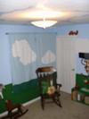 The homemade nursery curtains have hand-painted clouds to match the blue sky in the jungle theme nursery wall mural