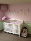 Makenzey's name spelled in letters on her pretty pink nursery wall behind her baby crib