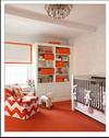 Pink white and orange baby room for a girl with a nursery chair upholstered in orange and white chevron fabric.