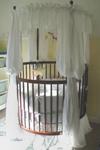 Yellow and white baby nursery decor with round crib and bedding collection