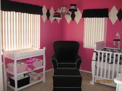 A baby girl nursery room with a painted diamond design pattern on a hot pink color wall