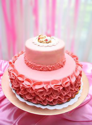 Homemade pink baby shower cake for twin girls with ruffles and homemade fondant sleeping baby cake topper.
